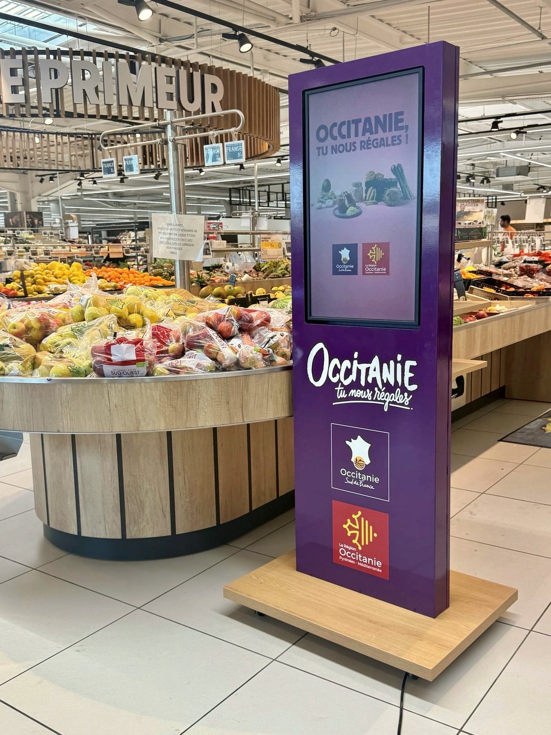Kakémono digital aux couleurs de la Région Occitanie, au rayon primeur d’une grande surface