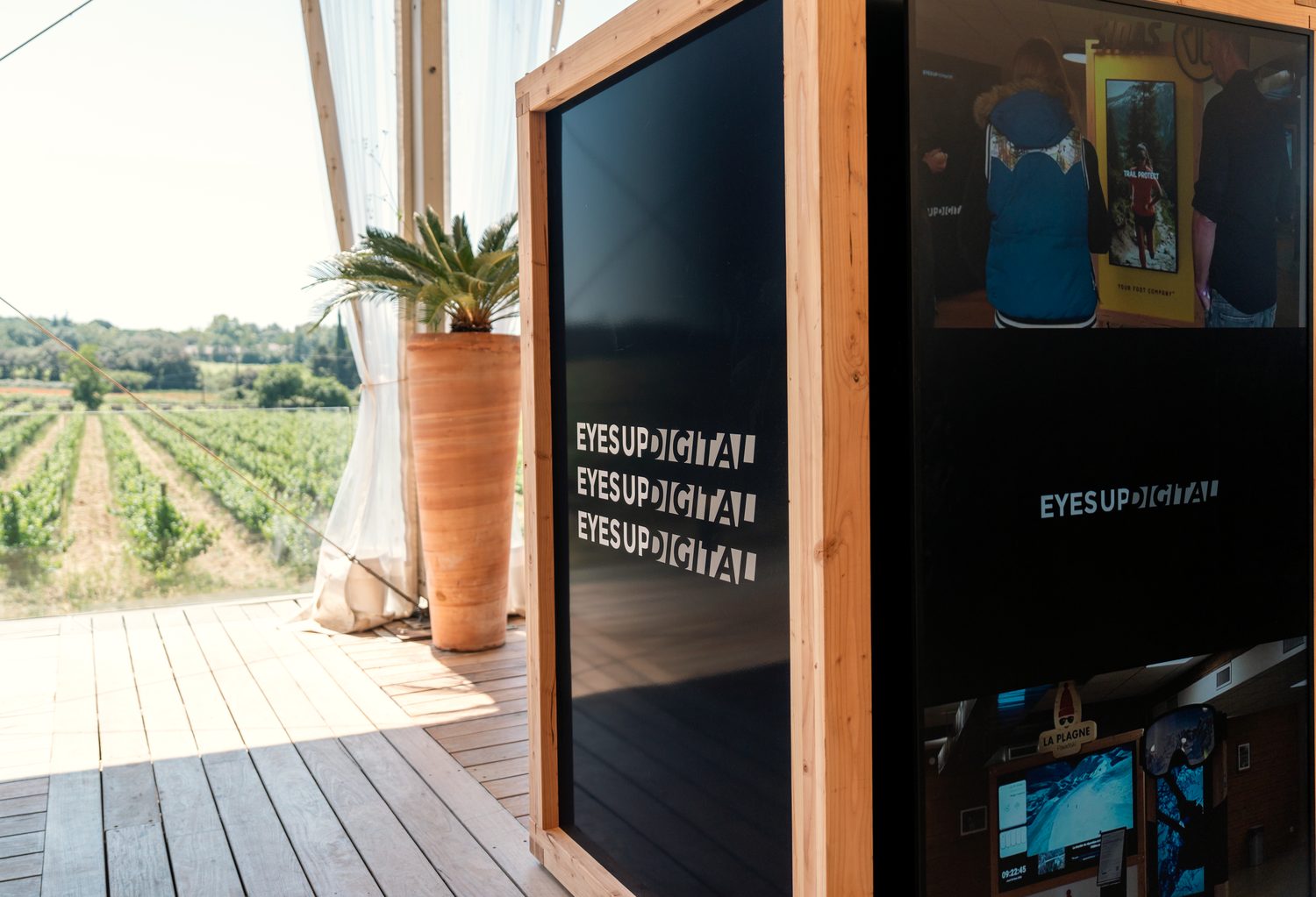 Cube digital en bois sur une terrasse de réception face aux vignes